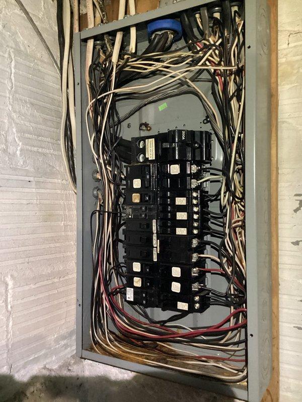 Conducted free electrical inspection of residential panel system. Observed aging infrastructure with disorganized wiring bundles and conduit installation against wooden structural elements. Panel inspection revealed multiple circuit breakers with inadequate labeling and suboptimal wire management that may require future organization to meet current electrical code standards.
