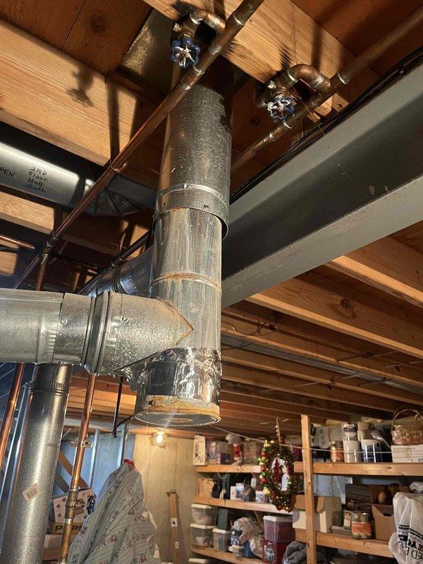 Responded to no heat call for furnace system where blower motor was non-operational. Inspection of 10+ year old basement unit revealed significant corrosion at duct connection points and a makeshift repair using foil tape on the PVC exhaust pipe. Replaced failed blower motor and properly sealed all compromised connections to restore proper system operation and airflow.