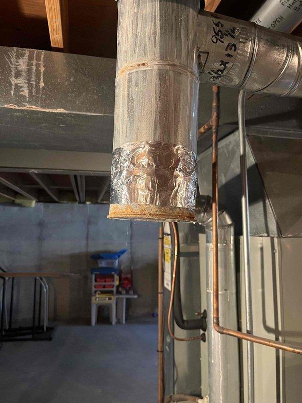 Responded to no heat call for furnace system where blower motor was non-operational. Inspection of 10+ year old basement unit revealed significant corrosion at duct connection points and a makeshift repair using foil tape on the PVC exhaust pipe. Replaced failed blower motor and properly sealed all compromised connections to restore proper system operation and airflow.