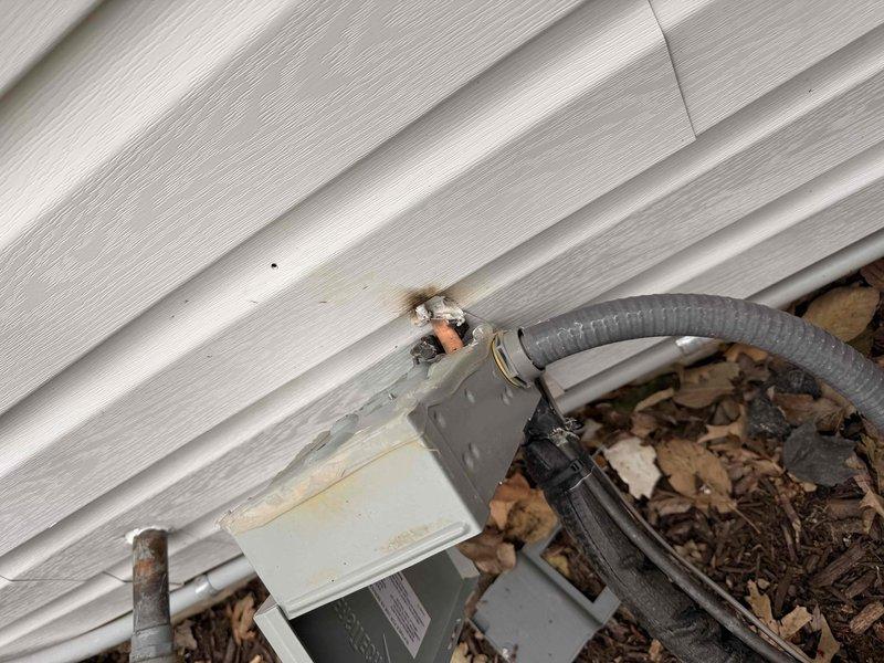 Conducted site assessment for installation of new electrical conductor from second-floor distribution panel to exterior AC disconnect switch. Inspection revealed complex cable routing through structural framework with multiple existing electrical and communication lines. Examined exterior connection point where service entrance will terminate, noting weathered junction box mounted on vinyl siding that will require proper sealing during installation to prevent moisture intrusion.