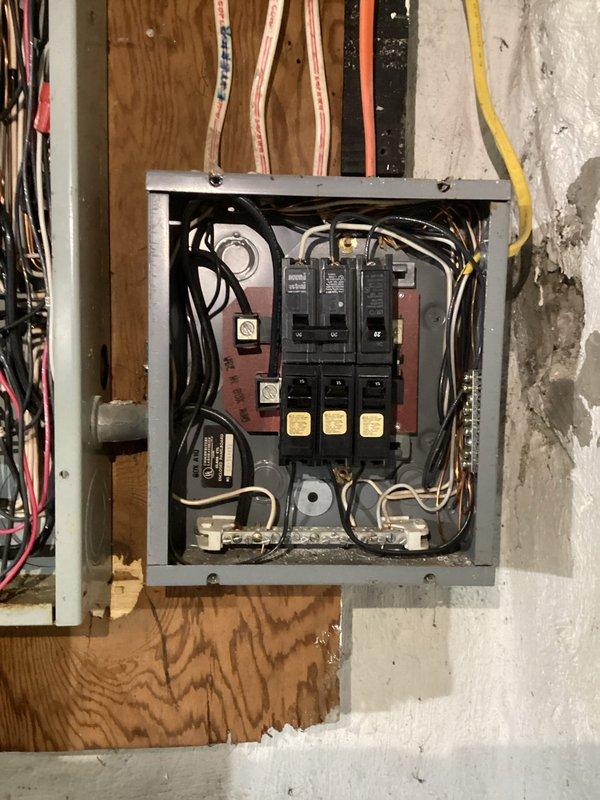 Conducted comprehensive electrical inspection of two distribution panels. First panel featured dual-column configuration with properly labeled circuit breakers including several 20A circuits and specialized red breakers. Second panel, mounted on plywood backing against masonry wall, showed signs of aging with exposed wiring bundles (black, white, red, yellow) and visible terminal connections. Both panels were operational with no immediate safety concerns identified.