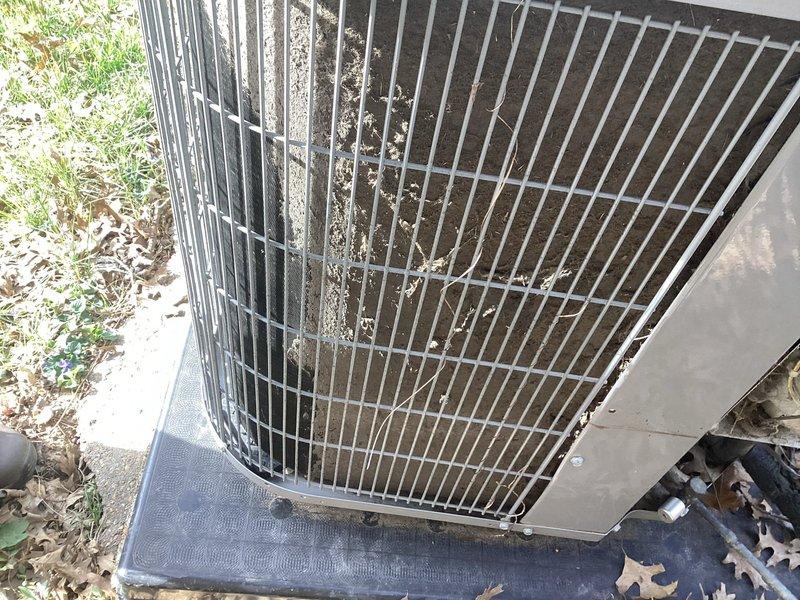 # Service Report: HVAC No Cooling Call

Responded to service call for 8-year-old Carrier system experiencing slow cooling with thermostat displaying service alert. Upon arrival, performed visual inspection of outdoor condenser unit and identified significant airflow restriction due to heavy accumulation of dirt, dust, and debris throughout aluminum cooling fin assembly. Debris buildup was particularly severe in lower portions of coil, with additional leaves, twigs, and organic matter collected on top protective grille and throughout unit exterior.

Performed thorough coil cleaning to restore proper airflow and heat transfer capacity. Removed protective grille to access condenser coil assembly. Cleared organic debris from top of unit and surrounding areas. Applied specialized coil cleaning solution and carefully cleaned cooling fins to remove embedded dirt and environmental contaminants without damaging delicate aluminum fin structure. Straightened any bent fins to maximize airflow effi