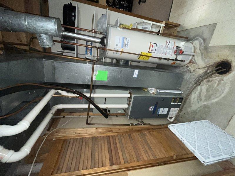 # HVAC Service Report - No Cooling Complaint

Responded to service call for non-operational air conditioning system on residential split system over 10 years old. Upon arrival, performed comprehensive diagnostic evaluation of both indoor air handler unit located in basement mechanical room and outdoor condensing unit positioned on exterior concrete pad.

Conducted visual inspection of indoor equipment, noting furnace/air handler configuration with adjacent water heater installation. Verified proper air filter placement and checked for obvious signs of electrical or mechanical failure. Examined ductwork connections and refrigerant line sets for damage or disconnection.

Proceeded to outdoor unit assessment, checking condensing unit for proper electrical supply at disconnect box. Tested capacitor functionality, contactor operation, and compressor response. Verified fan motor operation and inspected condenser coil condition for blockages or debris accumulation that could restrict airflow 