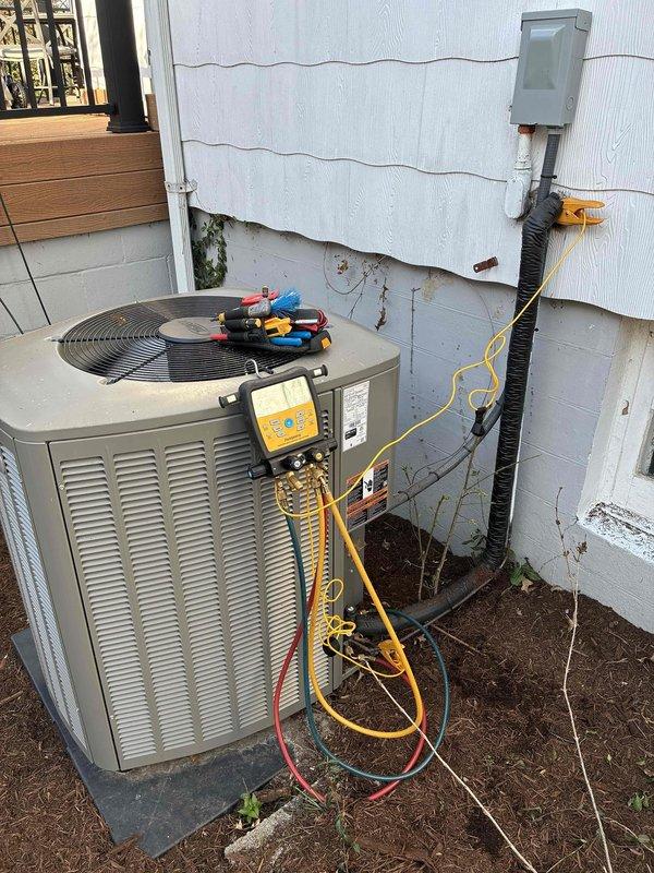 # Service Report: A/C System Performance Evaluation

Responded to service call for cooling system not maintaining set temperature on residential unit under 10 years old located in side yard. Upon arrival, performed comprehensive system diagnostics using digital manifold gauges to assess refrigerant pressures and system operation.

Conducted temperature measurements at supply ductwork, recording 42.2°F at the supply plenum, which falls within acceptable range for proper cooling operation. However, noted significant deterioration of duct insulation coating with peeling and flaking material on supply ductwork, which could contribute to reduced system efficiency and thermal loss. Flexible duct tape repairs visible on upper section of ductwork indicate previous maintenance attempts.

Connected professional diagnostic gauges to outdoor condensing unit to evaluate refrigerant charge levels, compressor performance, and overall system pressures. Unit installed on concrete pad with electrical se