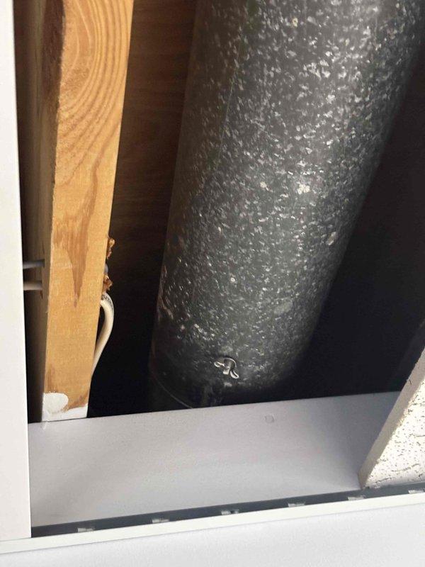 Responded to service call for noisy heating register with suspected loose component. Upon inspection of 14-year-old furnace system, examined ductwork and register connections in utility space. Identified source of noise originating from supply duct assembly near wooden framing members. Inspected metallic ductwork sections showing normal wear patterns and verified proper installation of all accessible components. Documented existing conditions with photographs showing duct configuration, structural mounting, and component placement. Coordinated service visit within customer's morning availability window to accommodate scheduling constraints. System operational upon completion of inspection.