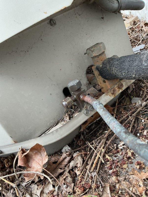# HVAC Service Completed

Responded to no-cool call for residential condensing unit that would not turn on and was producing unusual noise. Upon arrival, found outdoor unit with significant debris accumulation around base and perimeter, including dried leaves, twigs, and organic matter that had collected against cabinet and restricted airflow. Inspected condensing unit exterior, noting weathered cabinet with dirt buildup and signs of age. Cleared debris from around unit base and checked electrical connections at outdoor disconnect. Verified unit specifications and documented existing conditions with photos showing plumbing connections, cabinet condition, and debris accumulation. Unit required cleaning and further diagnostic evaluation to determine cause of reported strange noise and failure to start. Recommended thorough coil cleaning and electrical component testing to restore proper operation.