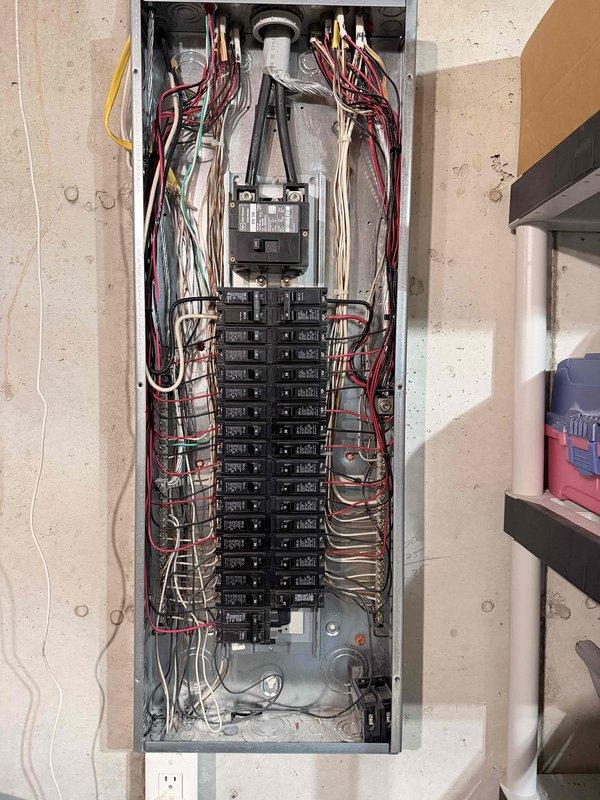 Completed comprehensive electrical safety inspection of residential property. Documented main electrical panel interior showing dual-column circuit breaker arrangement with main disconnect, verified proper wire routing and organization of conductor bundles, and confirmed grounding connections intact. Inspected exterior meter installation including digital utility meter, service entrance conduit, and weatherproof junction box, verifying all components mounted securely to structure with appropriate hardware and safety labeling in place.