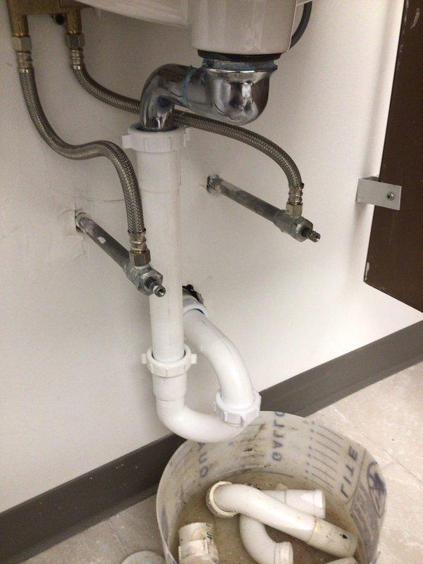 Successfully installed two 20" x 18" wall-hung sinks with lever handle faucets, shut-off valves, and ADA-compliant handicap accessories per specifications. Completed all drain assemblies using white PVC P-trap configurations with chrome tailpieces, connected braided stainless steel flexible supply lines to wall-mounted angle stops, and verified proper drainage and water flow. All installations tested and confirmed operational with no leaks detected.