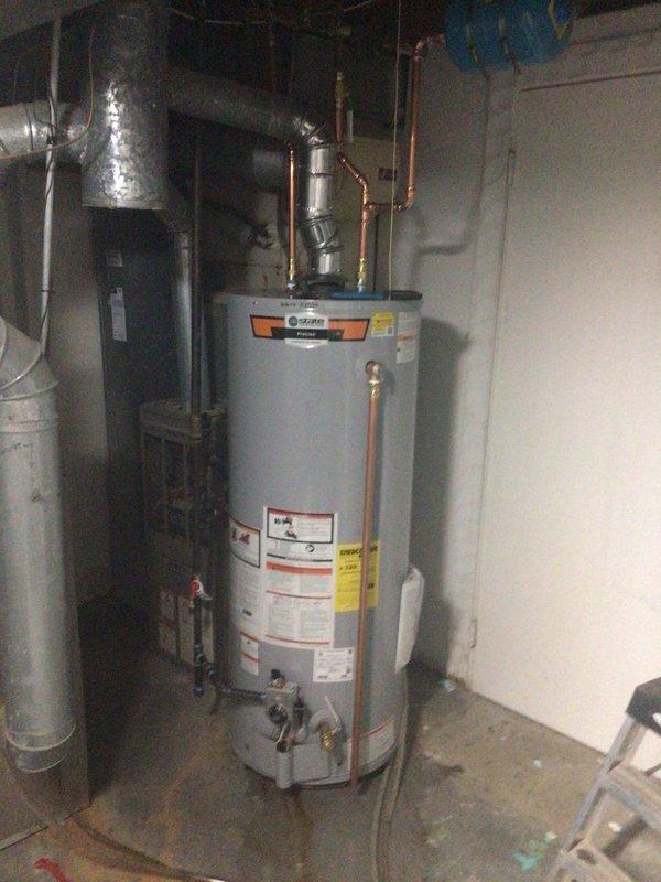 Installed a new 50-gallon tall gas water heater manufactured by RUUD in the mechanical room. Connected copper supply and discharge piping to the unit, ensuring proper integration with existing plumbing infrastructure. Applied permit identification sticker for permit #26PLU-05454 and verified all warning labels, energy guide information, and manufacturer specifications were clearly visible on the installed unit.