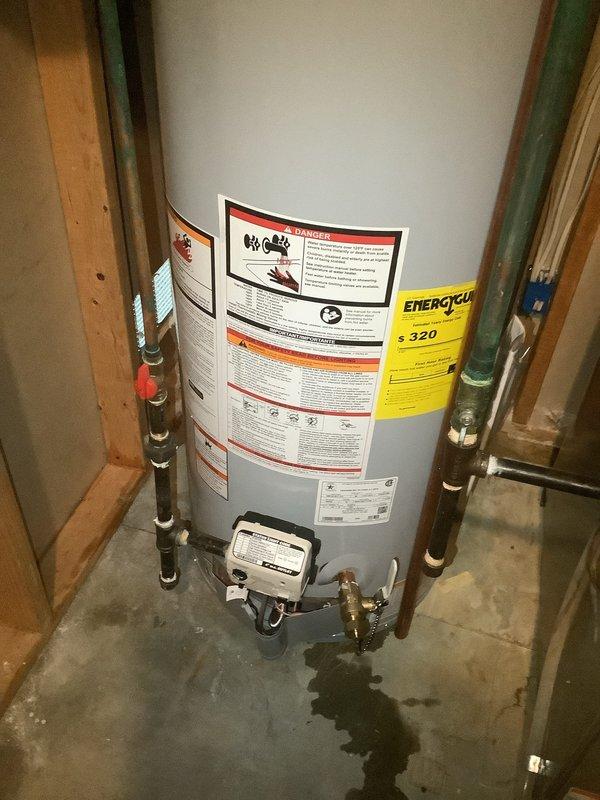 Installed a 40-gallon tall gas water heater in residential basement utility room between wooden framing studs. Completed copper piping connections with brass fittings to top of unit, installed blue water filtration component, and connected all supply and discharge lines per code requirements. Installation performed under permit #26PLU-05492 with proper identification sticker applied to unit.