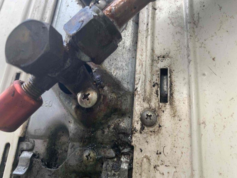 Responded to service call for one-year-old mini split system blowing warm air instead of cooling. Upon inspection, discovered severe contamination and corrosion within the indoor unit, including extensive dark staining, moisture damage, and deterioration of internal components. Found corroded copper piping connections and valve assembly with significant oxidation around fittings, likely related to previous lineset leak repair completed one month after initial installation. Documented conditions with photographic evidence showing compromised interior surfaces, accumulated debris, and hardware corrosion affecting system performance. Unit requires further evaluation to determine if contamination has damaged refrigerant circuit or if additional repairs beyond previous lineset work are necessary to restore proper cooling operation.