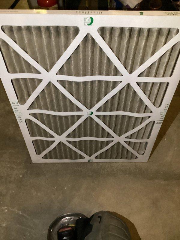 Responded to no cooling complaint on 4-year-old residential system. Upon inspection, found severely restricted airflow due to dirty air filter causing reduced cooling capacity. Removed and photographed heavily loaded filter from air handler unit located in basement mechanical room. Replaced filter with new pleated media filter. Verified proper airflow restoration and system operation. Unit returned to normal cooling function.