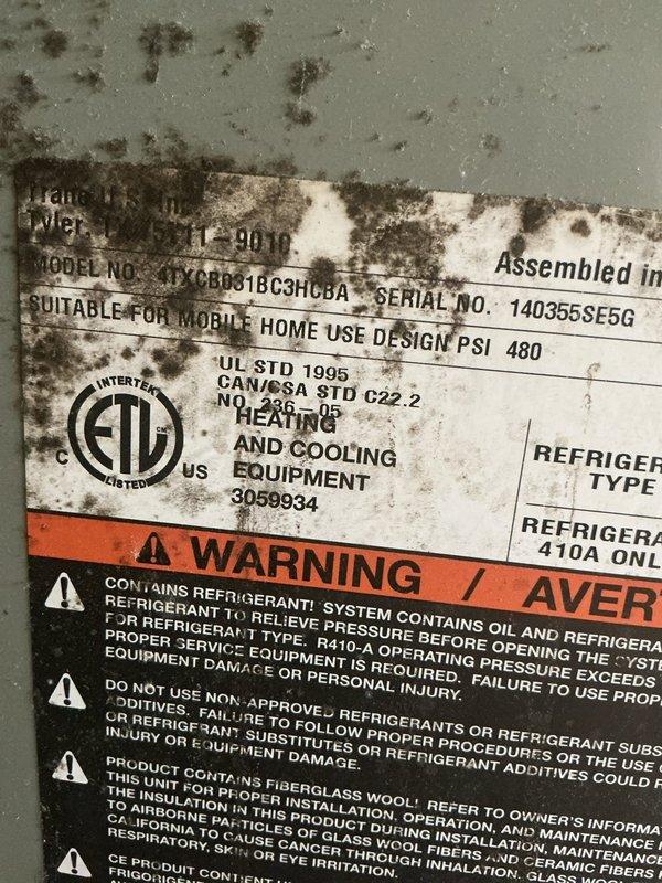 # HVAC Service Call - No Cooling Complaint

Responded to service call for Trane air conditioning unit (Model: 4TXCB031BC3HCRAA, Serial: 140365SE5G) with reported issues of no cooling and inoperative fan. Unit located on side of home, approximately 10 years old, designed for mobile home installation utilizing R-410A refrigerant.

Upon arrival, contacted customer per instructions and proceeded with diagnostic assessment. Performed visual inspection of outdoor condensing unit, noting significant mold and mildew contamination on exterior cabinet surfaces and manufacturer data plates, indicating prolonged exposure to moisture and environmental elements. Contamination patterns suggested potential drainage issues or inadequate airflow around unit perimeter.

Conducted electrical system diagnostics including:
- Verified power supply at disconnect
- Tested contactor operation and contacts
- Checked capacitor values for compressor and fan motor
- Inspected control board for visible damage or bur