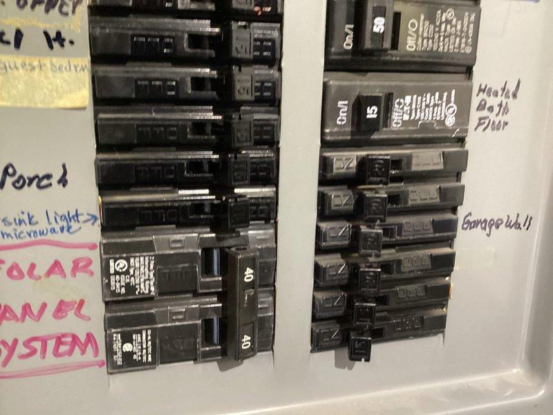 Completed comprehensive electrical home audit and safety inspection of residential electrical system. Documented main electrical panel configuration, including 200-amp single-pole breakers and circuit distribution layout, noting proper QEC common trip functionality and circuit labeling for various home systems including porch, kitchen appliances, microwave, garage, and solar panel system integration. All breaker switches operational with visible amperage ratings confirmed; panel showed normal wear consistent with age but remains in serviceable condition with adequate circuit organization and handwritten circuit identification present.