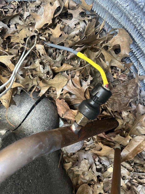 Responded to no cool call on 5-year-old residential AC system with ground-level condenser unit located at side of home. Upon arrival, found significant debris accumulation including dried leaves around outdoor unit base and components. Connected manifold gauge set to service ports to diagnose system pressures and refrigerant charge. Performed visual inspection of condenser unit, noting outdoor exposure conditions and general wear patterns on equipment. Cleared debris from around unit and documented equipment condition with photos showing service valve connections and accumulated foreign material that could restrict airflow and reduce cooling efficiency.