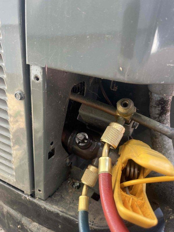 Responded to no cool call on 5-year-old residential AC system with ground-level condenser unit located at side of home. Upon arrival, found significant debris accumulation including dried leaves around outdoor unit base and components. Connected manifold gauge set to service ports to diagnose system pressures and refrigerant charge. Performed visual inspection of condenser unit, noting outdoor exposure conditions and general wear patterns on equipment. Cleared debris from around unit and documented equipment condition with photos showing service valve connections and accumulated foreign material that could restrict airflow and reduce cooling efficiency.