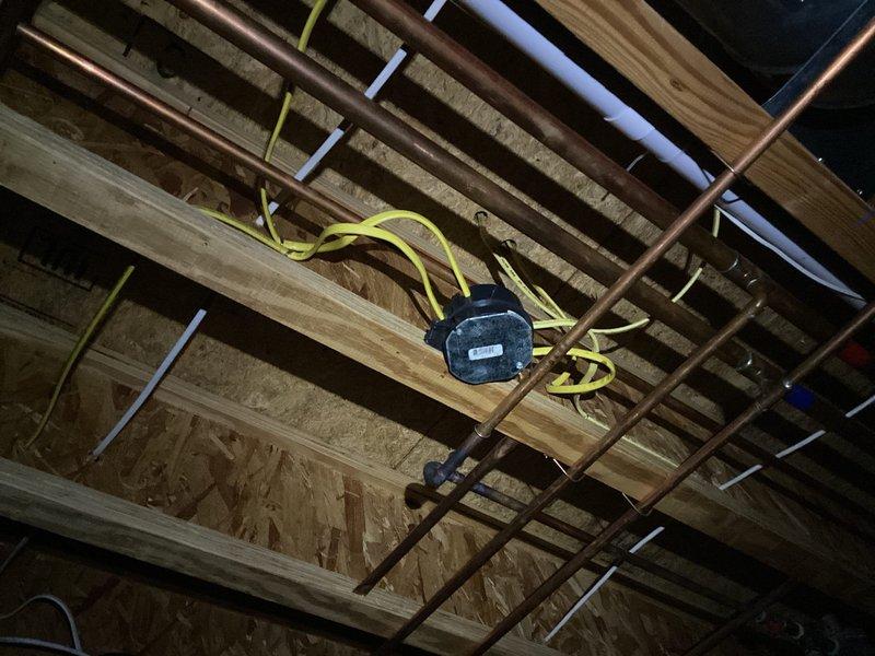 Completed comprehensive electrical inspection of unfinished ceiling space, documenting exposed electrical systems including yellow Romex wiring, junction boxes, and conduit routing through ceiling joists. Photographed existing MEP installations showing copper plumbing, PVC piping, and electrical distribution to verify proper installation methods and identify any code compliance concerns for homeowner records.