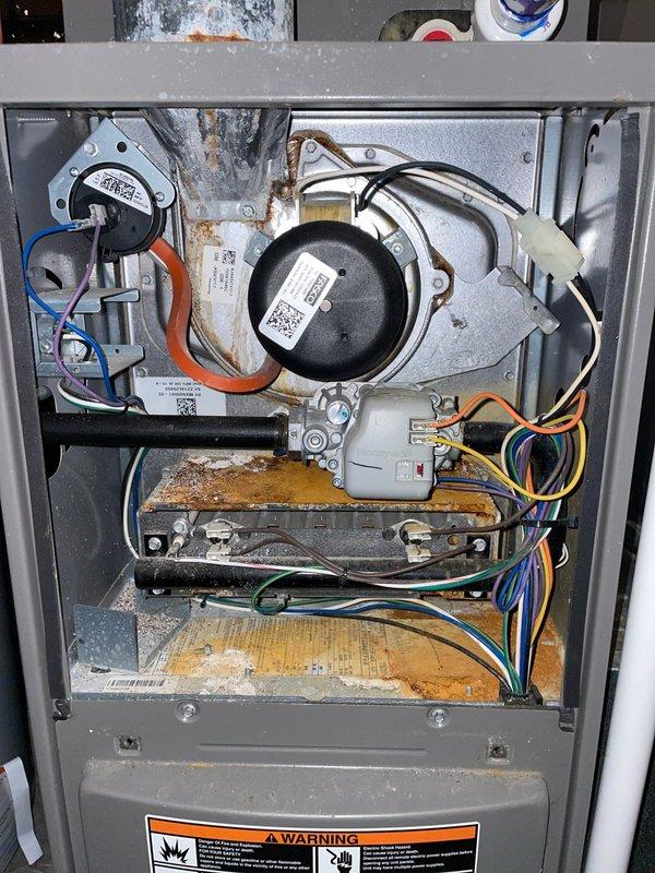 Replaced defective high limit switch on furnace system. Unit displayed signs of significant corrosion and moisture damage throughout the cabinet interior, with extensive rust visible on drip pans and base surfaces. Accessed control board compartment, removed failed high limit switch, and installed new replacement part. Verified all electrical connections were secure and tested system operation to ensure proper cycling and safety controls functioning correctly.