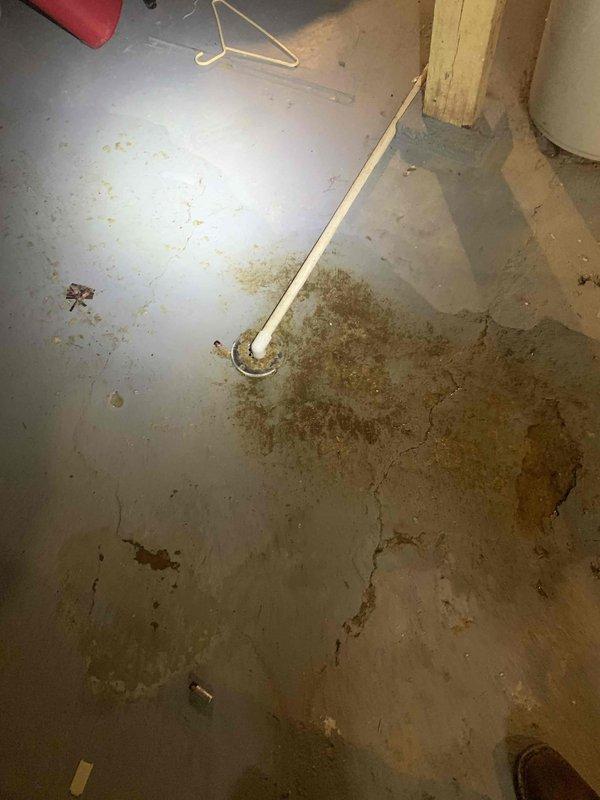 # Plumbing Service - Ground Water Drain

Responded to basement drainage issue where water was actively discharging from floor drain. Upon investigation, determined the problem was directly correlated with HVAC system operation—water level would rise when air conditioning unit was running and recede when system was shut off.

Diagnosed the issue as a condensate drain line improperly connected to or overwhelming the basement floor drain system. Cleared debris and obstructions from the affected drain using appropriate plumbing tools. Inspected condensate drainage pathway and verified proper flow away from the floor drain. Tested system by running the air conditioning unit and confirmed water was no longer backing up through the basement drain. Floor showed evidence of previous water infiltration and staining, consistent with recurring drainage issues prior to service.