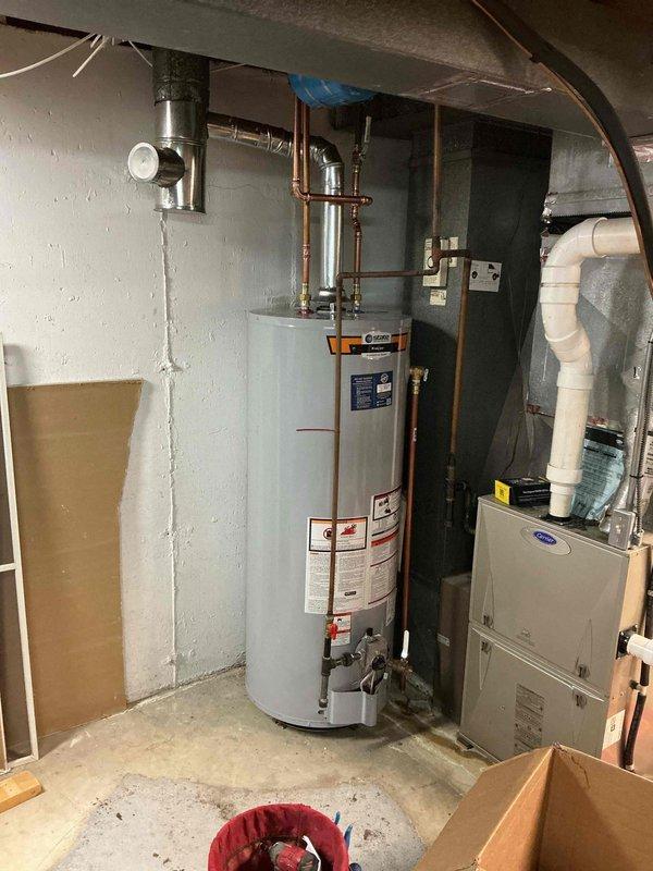 Completed installation of a 50-gallon tall gas water heater in basement utility area under permit 26PLU-06217. All copper supply lines, pressure relief valve, gas connections, and venting were properly installed per code requirements. Blue expansion tank was mounted to floor joists, all connections were tested for leaks, and plumbing identification sticker was affixed to the unit.