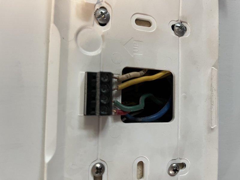 Responded to no-cool service call for 10-year-old Lennox system with unreadable thermostat display. Upon arrival, confirmed HVAC system was otherwise operational but thermostat screen was not functioning properly. Removed existing thermostat from wall and documented wiring configuration showing standard multi-conductor connections including R, Y, G, and C wires with wire nuts securing common connections. Diagnosed 11-year-old thermostat as failed unit beyond repair due to display malfunction. Removed defective thermostat and prepared wall plate for replacement installation. System restored to normal operation with readable display and full functionality.