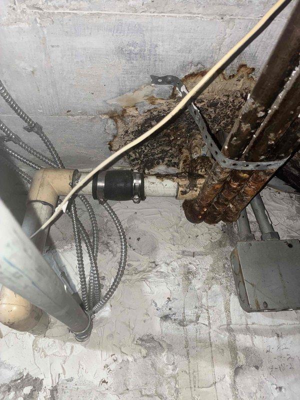 Responded to emergency call regarding water accumulation on refrigerant lines of three rooftop HVAC units. Accessed equipment through attic space using ladder to inspect units and surrounding plumbing infrastructure. Upon inspection, discovered significant corrosion on adjacent plumbing pipes including heavily rusted horizontal piping with deteriorated metal fittings and support brackets. Confirmed HVAC refrigerant lines were operating normally with proper condensation patterns. Determined water source was from corroded plumbing system rather than HVAC equipment malfunction. Documented extensive rust damage on metal pipes, fittings, and mounting hardware, along with moisture-related deterioration in mechanical space. Advised customer that leak originated from building plumbing infrastructure and not from HVAC units.