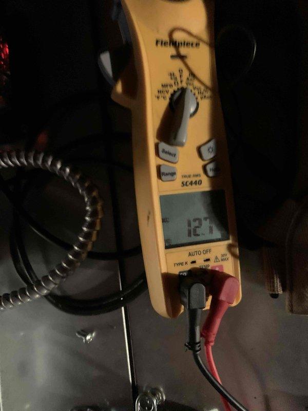 Responded to no-cooling call for two attic-mounted A/C units less than one year old. Upon arrival, performed diagnostic testing using clamp meter to measure electrical current and voltage at system components. Inspected both units in attic space, checking condensate drain lines, electrical connections, and refrigerant pressures. Units tested operational with amperage reading of 12.7 amps recorded during diagnostic process.