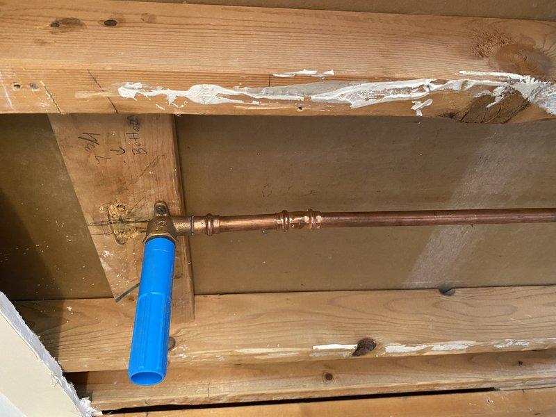 Completed plumbing rough-in installation for residential project including water supply lines and drainage system. Installed copper piping with brass fittings and water filtration component in upper level framing, along with PVC drainage assembly in lower level with proper venting and junction configurations. Performed water pressure testing to verify system integrity, followed by concrete patching of floor trenches where piping was installed. Retrieved testing equipment after successful inspection approval and completed final fixture installation including shower head in master bathroom.