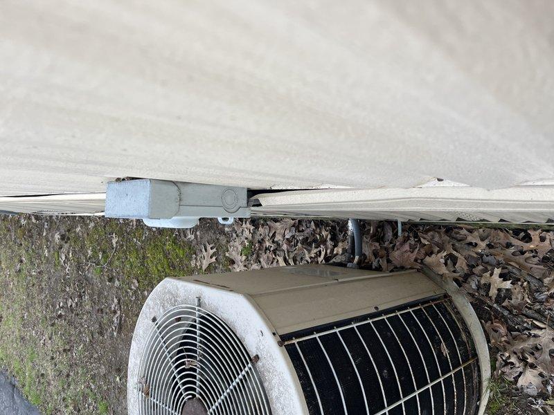 Responded to no cooling complaint on aging outdoor condenser unit located in side yard. Upon arrival, found unit with significant environmental wear, debris accumulation, and biological growth on surrounding surfaces. Performed diagnostic evaluation of system operation, inspected condenser coil condition through protective grille, and assessed electrical components including disconnect box. Documented equipment condition showing weathered exterior casing, darkened metal grating from oxidation, and dirt buildup affecting unit performance. Identified contributing factors to warm air discharge and provided recommendations for necessary repairs to restore proper cooling function.