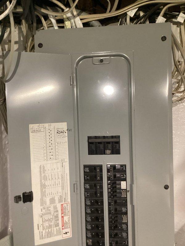 Completed complimentary electrical inspection of main service panel and distribution system. Documented current panel configuration showing dual columns of circuit breakers with main disconnect switches, verified panel directory labeling on interior door, and assessed overall system condition. Photographed wire management and cable routing above panel box to document existing installation for homeowner records.