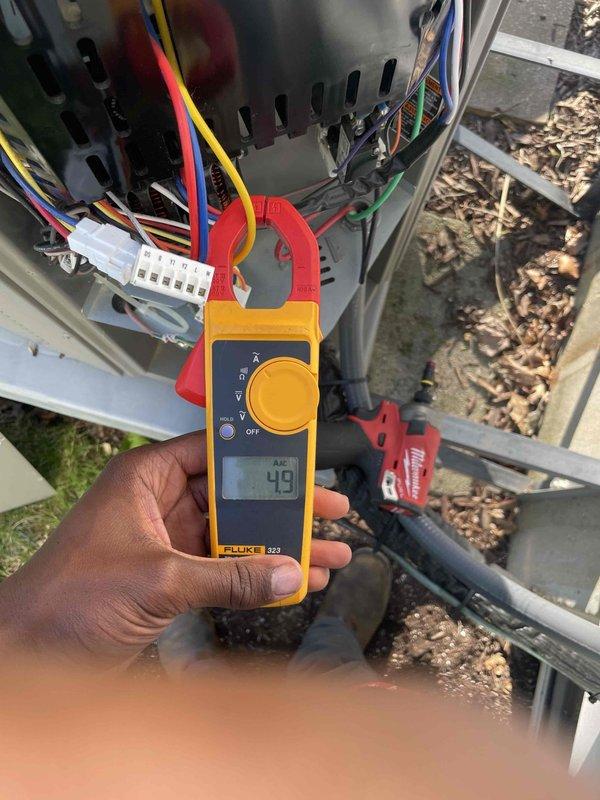Performed comprehensive cooling system tune-up on outdoor condensing unit located in side yard. Conducted electrical diagnostics using clamp meter, measuring amperage draw of 49 amps on compressor circuit, and inspected all wire connections at terminal block. Removed access panels to examine condenser coils and internal components, verified proper operation of all electrical connections, and completed standard maintenance procedures on unit under 10 years old per Home Depot service agreement specifications.