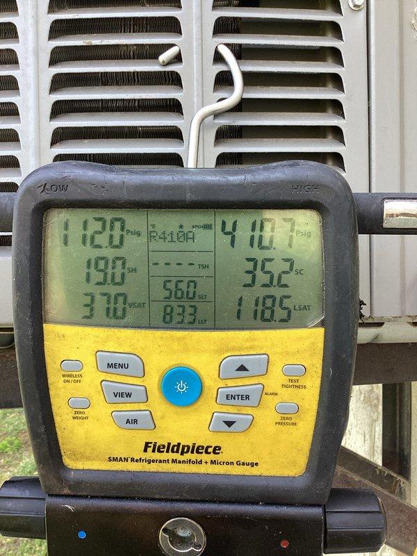 Responded to thermostat error code 413 indicating high pressure switch fault on condenser unit. Upon arrival, connected manifold gauges and confirmed system pressures were significantly elevated above normal operating parameters. System currently overcharged due to previous service incident in November where refrigerant leaked during gauge connection and 3 pounds of R-410A were added to a system with 6 pound 8 ounce factory charge specification. Utilized recovery machine to properly evacuate refrigerant from system into recovery tank. Measured and documented pressures showing high-side reading of 410.7 PSIG with ambient temperature of 65°F, confirming overcharge condition. After complete refrigerant recovery, recharged system to manufacturer specifications of 6 pounds 8 ounces of R-410A refrigerant. Verified proper superheat and subcooling values, cleared high pressure switch error, and confirmed system returned to normal operation with appropriate operating pressures and temperatures.