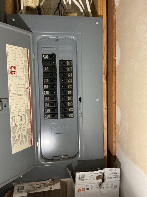 Met onsite to assess electrical system for complete rewire estimate. Inspected existing electrical infrastructure including two gray metal circuit breaker panels mounted on wooden framing in unfinished space, documenting current breaker configuration, panel condition, and surrounding construction environment. Photographed open panel revealing dual vertical columns of circuit breakers, panel door labeling with handwritten circuit notations, and secondary closed panel for comprehensive scope development. Evaluated exposed framing, unfinished wall conditions, and accessibility factors to determine labor requirements and material specifications for proposed electrical system upgrade.