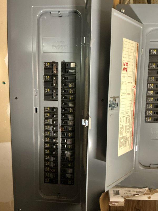 Met onsite to assess electrical system for complete rewire estimate. Inspected existing electrical infrastructure including two gray metal circuit breaker panels mounted on wooden framing in unfinished space, documenting current breaker configuration, panel condition, and surrounding construction environment. Photographed open panel revealing dual vertical columns of circuit breakers, panel door labeling with handwritten circuit notations, and secondary closed panel for comprehensive scope development. Evaluated exposed framing, unfinished wall conditions, and accessibility factors to determine labor requirements and material specifications for proposed electrical system upgrade.