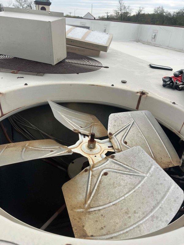 Performed leak search on rooftop BAX-15 unit experiencing second stage compressor failure. Upon inspection, found heavily soiled condenser coil with significant dust and debris accumulation affecting heat transfer efficiency. First stage heating operation confirmed functional while second stage compressor remained inoperative. Documented equipment condition showing aged fan assembly with visible weathering and deteriorated housing components. Customer previously informed that replacement parts are no longer available for this discontinued unit model.