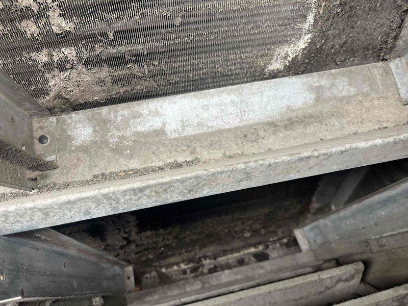 Performed leak search on rooftop BAX-15 unit experiencing second stage compressor failure. Upon inspection, found heavily soiled condenser coil with significant dust and debris accumulation affecting heat transfer efficiency. First stage heating operation confirmed functional while second stage compressor remained inoperative. Documented equipment condition showing aged fan assembly with visible weathering and deteriorated housing components. Customer previously informed that replacement parts are no longer available for this discontinued unit model.