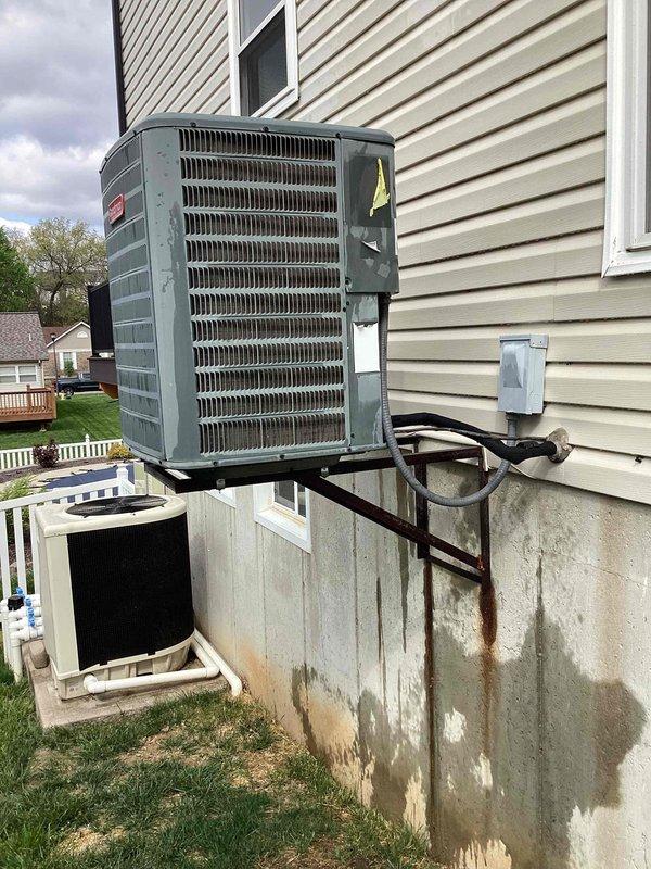 Completed comprehensive cooling season tune-up on 14-year-old residential air conditioning system. Performed standard maintenance protocol including inspection of outdoor condenser unit mounted on exterior wall bracket, verified refrigerant line connections, checked electrical disconnect, and assessed overall system operation. Unit showed age-appropriate wear with visible exterior weathering and foundation staining below mounting hardware, but system functioned within normal parameters upon completion of preventative maintenance service.