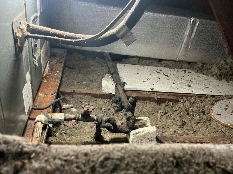 Performed diagnostic evaluation on residential air conditioning system over 10 years old located at side of home. Accessed crawl space and inspected mechanical components including refrigerant lines, shut-off valves, and ductwork. Assessed condition of piping system, connections, and equipment housing in confined utility area beneath structure.