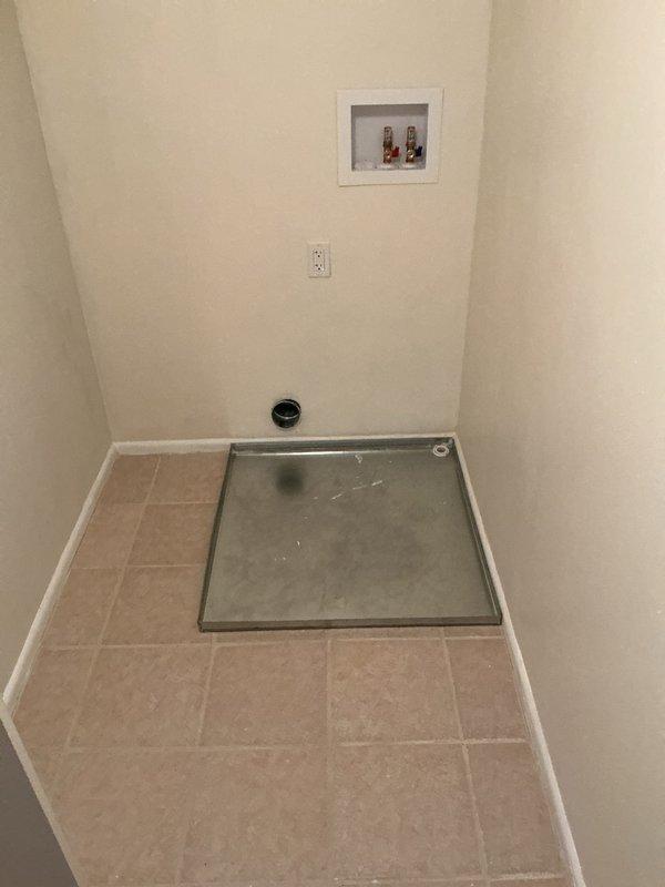 Responded to callback regarding washing machine drain pan positioning. Upon inspection, confirmed drain pan was installed too close to wall, preventing proper dryer installation and ventilation clearance. Appliance installer had previously notified homeowner that minimum 6-inch clearance from wall is required for appliance delivery and proper vent connection. Documented existing installation with photos showing drain pan placement, electrical outlet configuration, water supply connections, and floor drain location in utility room. Issue requires drain pan relocation to meet appliance installation specifications and allow adequate spacing for dryer vent routing.