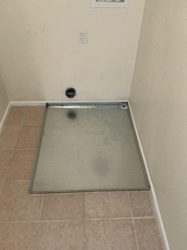 Responded to callback regarding washing machine drain pan positioning. Upon inspection, confirmed drain pan was installed too close to wall, preventing proper dryer installation and ventilation clearance. Appliance installer had previously notified homeowner that minimum 6-inch clearance from wall is required for appliance delivery and proper vent connection. Documented existing installation with photos showing drain pan placement, electrical outlet configuration, water supply connections, and floor drain location in utility room. Issue requires drain pan relocation to meet appliance installation specifications and allow adequate spacing for dryer vent routing.