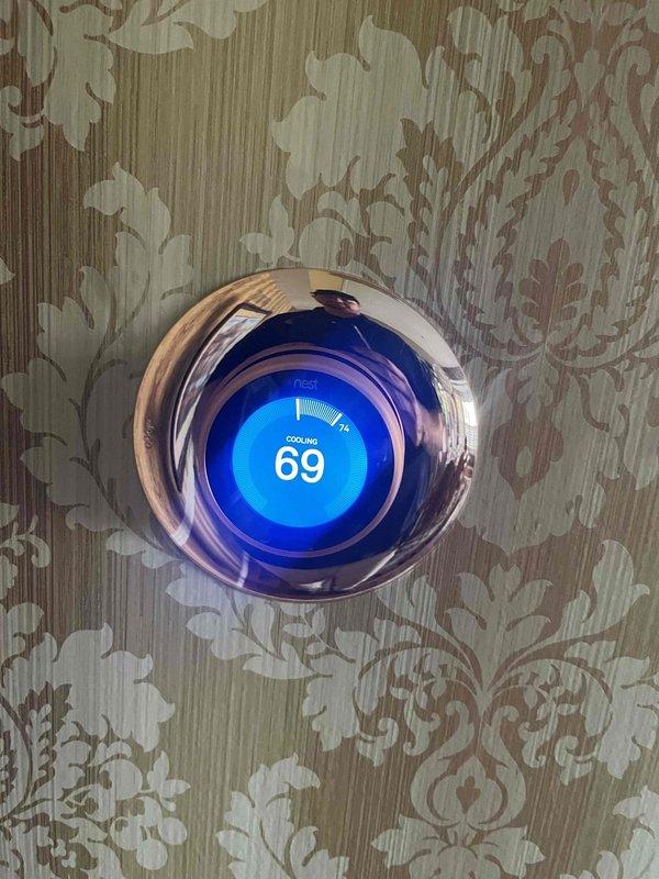 Completed preventive maintenance tune-up on 8-year-old residential split-system air conditioning unit located on exterior side of home. Performed comprehensive cooling system inspection including condenser unit evaluation, refrigerant level check, electrical connection testing, and thermostat functionality verification. System operating properly with Nest thermostat displaying 69°F in cooling mode and outdoor condenser unit showing normal operation with clean airflow through heat exchanger coils.