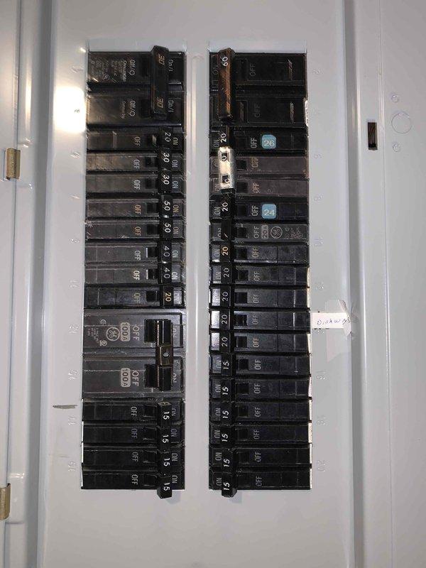 Completed comprehensive electrical inspection of residential basement utility area. Documented two electrical panels including one open panel revealing multiple circuit breakers with various amperage ratings (15A, 20A, 30A, and 100A main breakers), verified proper wire routing and connections, and noted presence of AFCI/GFCI breakers with blue test buttons in right column. Inspection revealed significant water staining on concrete block wall beneath left electrical panel indicating previous or ongoing moisture intrusion that requires monitoring for potential electrical safety concerns. Photographed exposed wiring, conduit routing including white PVC and yellow electrical cables, panel configuration, and overall condition of electrical infrastructure for documentation purposes.