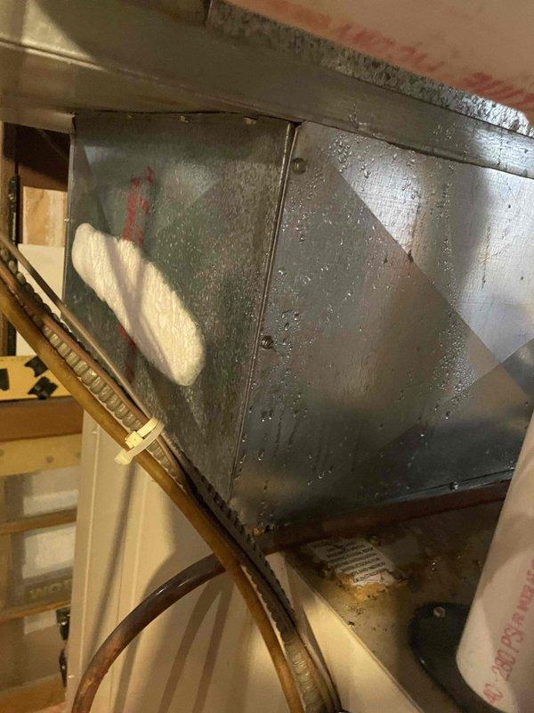 Responded to callback for reported AC leak that could not be previously replicated due to weather conditions. Upon arrival, accessed air handler unit located at rear of home and inspected system during active cooling operation. Found significant condensation accumulation on supply plenum and flex ductwork in attic space, with water droplets visible on metal surfaces and duct insulation. Identified condensation as source of reported leak rather than refrigerant or drain line issue. Verified drain pan and condensate line were clear and functioning properly. System operating within normal parameters with adequate airflow through blower assembly.