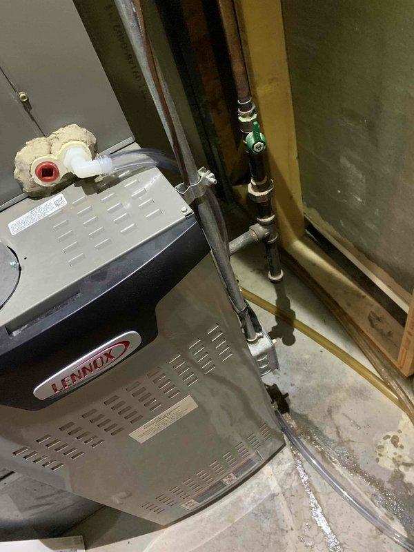 Responded to service call for recurring AC condensate drain hose disconnection causing water leakage near furnace and indoor unit, with water damage occurring on carpeting. Upon inspection of 11-year-old Lennox system, found condensate drain line had been temporarily repaired previously but connection remained inadequate and prone to separation. Evaluated drain routing from evaporator coil and identified improper fitting connection at transition point near air handler. Disconnected existing temporary repair, cleaned pipe connections, and installed proper PVC coupling with primer and cement to create permanent sealed connection. Verified drain line slope for proper gravity drainage and secured all connections. Tested condensate drainage system by pouring water through drain pan to confirm positive flow without leaks at repair point. Inspected surrounding area for water damage and advised on monitoring carpet for complete drying. System operational with secure drain connections establish