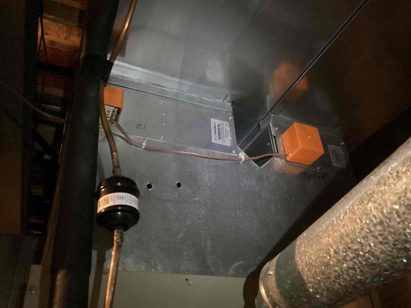 # HVAC Zoning System Damper Noise Diagnosis and Inspection

Responded to customer report of noise originating from damper system. Performed comprehensive inspection of HVAC zoning control system including ZoneFirst control panel with dual circuit boards and associated wiring connections. Verified all electrical connections at terminal blocks and examined control board functionality. Inspected damper actuators and mechanical components throughout ductwork system in attic space. Examined main supply plenum, branch ductwork, and damper assemblies for proper operation and potential noise sources. Checked refrigerant lines, mechanical supports, and duct mounting hardware for secure installation. Tested zone control system operation through multiple cycles to identify intermittent noise conditions. Documented system configuration and current operating conditions with photographic records. System zoning controls and damper mechanisms assessed for proper functionality and noise mitigation requ