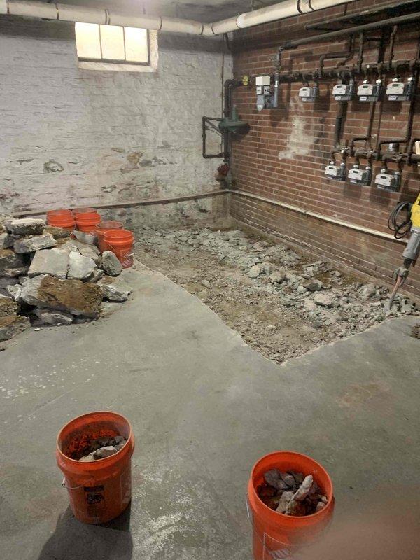 Completed commercial piping installation in basement utility room under plumbing permit PL26-000193 and right of way permit ROW26-000083. Excavated and removed existing concrete flooring to access subsurface for new underground plumbing infrastructure installation. Coordinated work around existing utility meter arrays and building systems mounted on brick wall, ensuring no disruption to active gas and water distribution equipment during excavation and piping installation phases.