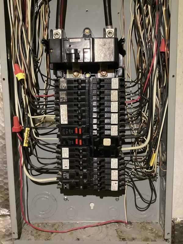 Completed comprehensive electrical panel rejuvenation and surge protector installation on residential service entrance equipment. Inspected and documented existing panel configuration showing main disconnect, dual-column circuit breaker arrangement with approximately 20-30 individual breakers, and multiple branch circuit wiring in standard color coding. Performed necessary upgrades to enhance system protection and reliability per current electrical code requirements.