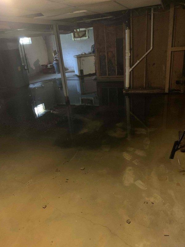 Responded to basement drain clog resulting in significant flooding throughout the unfinished basement area. Upon arrival, found extensive standing water covering the concrete floor with water pooling at varying depths around support columns, storage units, and exposed wall framing. Identified and cleared the clogged drain line causing the backup. Verified proper drainage flow was restored and water began receding from the basement floor. Documented existing water damage conditions with photos for customer records.