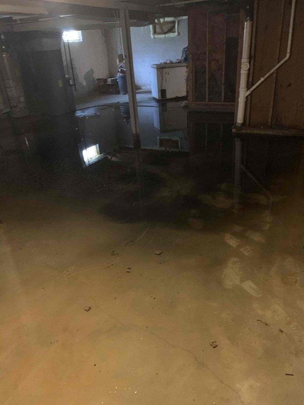 Responded to basement drain clog resulting in significant flooding throughout the unfinished basement area. Upon arrival, found extensive standing water covering the concrete floor with water pooling at varying depths around support columns, storage units, and exposed wall framing. Identified and cleared the clogged drain line causing the backup. Verified proper drainage flow was restored and water began receding from the basement floor. Documented existing water damage conditions with photos for customer records.