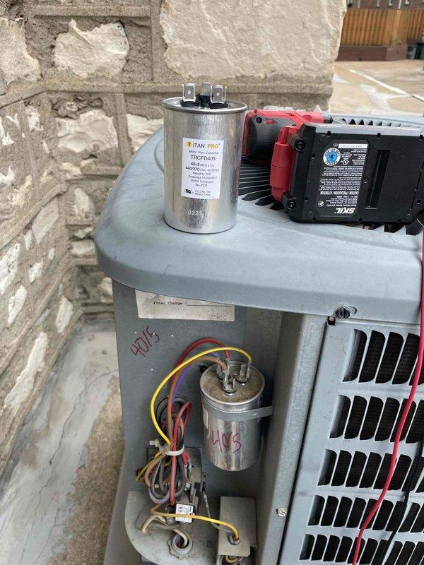 Replaced failed dual capacitor on outdoor condensing unit. Removed defective 40/5 MFD capacitor, installed new TITAN PRO replacement, and verified proper electrical connections. Tested unit operation with multimeter to confirm proper voltage readings and successful system startup.